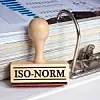 Stempel mit der Aufschrift ISO-Norm in einem Aktenordner