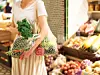 Frau im Supermarkt mit Netzen, in denen Obst und Gemüse steckt