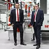 Dominik Hauns und Markus Wöppermann von SEW-Eurodrive vor einer Maschine stehend.