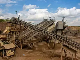 View of open-pit mine machinery with sifters and belt conveyors in basalt quarry
