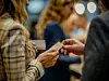 Two individuals exchanging business cards in a room at a networking event, emphasizing professional relationship building