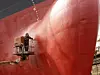 Workers working in a shipyard and painting in naval industry