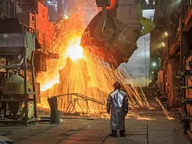 Hot steel pouring from big casting ladle into a mold in an iron foundry.