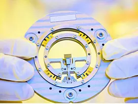 An Intel manufacturing technician at Fab 11X in Rio Rancho, New Mexico, holds a bond module carrier containing a single silicon photonics chip in January 2024. These Intel products enable future data center bandwidth growth and next-generation 5G deployments using smaller form factors and higher speeds. (Credit: Intel Corporation)