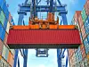 Roter Standard-Container, der in einem Hafen durch einen Kran bewegt wird.