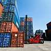 Gestapelte Container auf einem Gelände und ein Gabelstapler im Vordergrund
