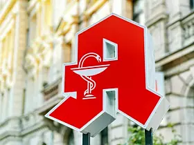 Logo Apotheke vor Häuserfassade
