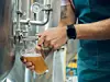 Man füllt eine Bierprobe aus einem Brauereibehälter ab