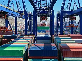 Luftaufnahme eines farbenfrohen Containerhafens und Logistikterminals im Kranbereich beim Be- und Entladen eines Containertankschiffs