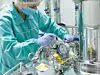 Pharmaceutical factory woman worker in protective clothing operating production line in sterile environment