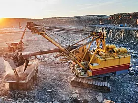 Bagger schaufelt Gestein auf einen Lkw