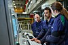 Drei Fabrikmitarbeitende bedienen gemeinsam eine industrielle Steuerkonsole.